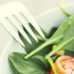 Ensalada saludable con verduras frescas, tomate, espinaca y queso en un plato blanco.